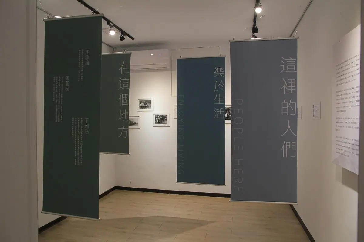 Hanging photographic scrolls of resident oral history portraits in the "Fragments of Light" zone