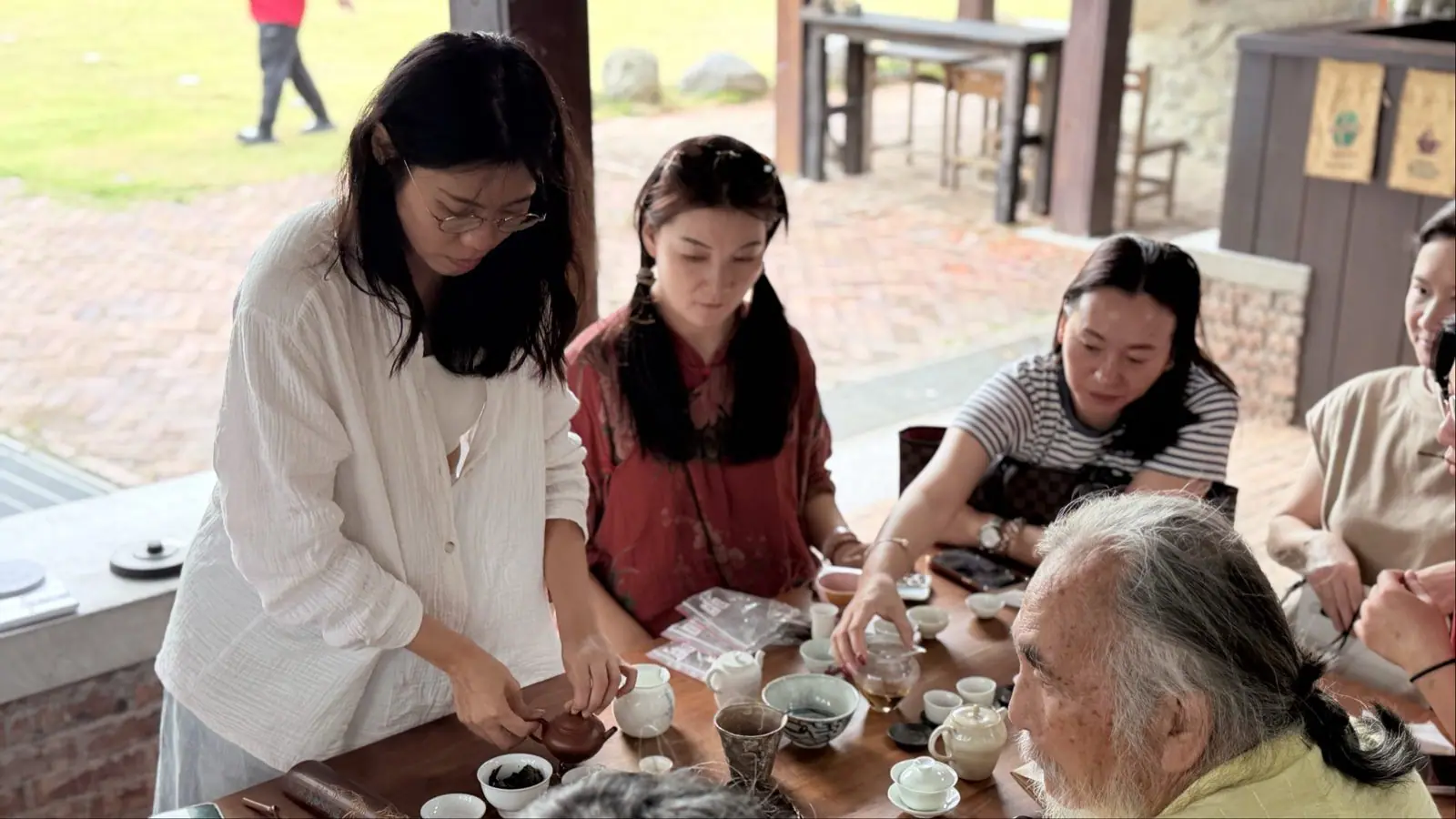 チームと長老たちが囲んでお茶を飲み、ブランド育成ワークショップの成果を語り合う様子